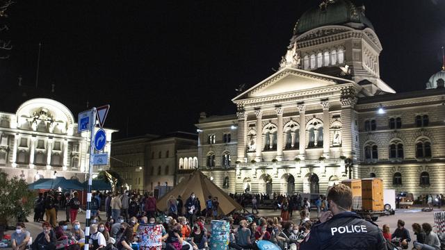 Des manifestants et manifestantes ont investi la Place fédérale à Berne lundi tôt dans la matinée. [Keystone - Peter Schneider]