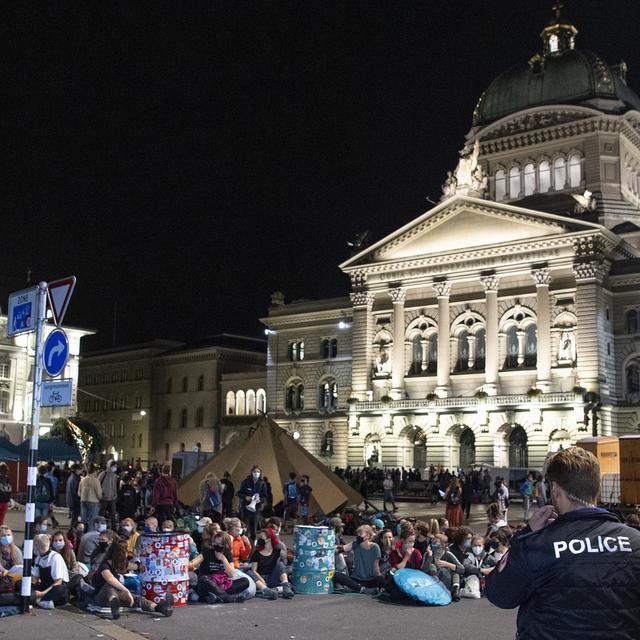 Des manifestants et manifestantes ont investi la Place fédérale à Berne lundi tôt dans la matinée. [Keystone - Peter Schneider]