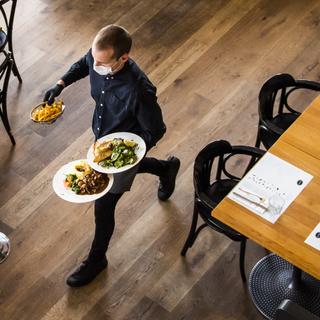 Un serveur au travail dans une brasserie lausannoise au mois de mai 2020. [Keystone - Jean-Christophe Bott]