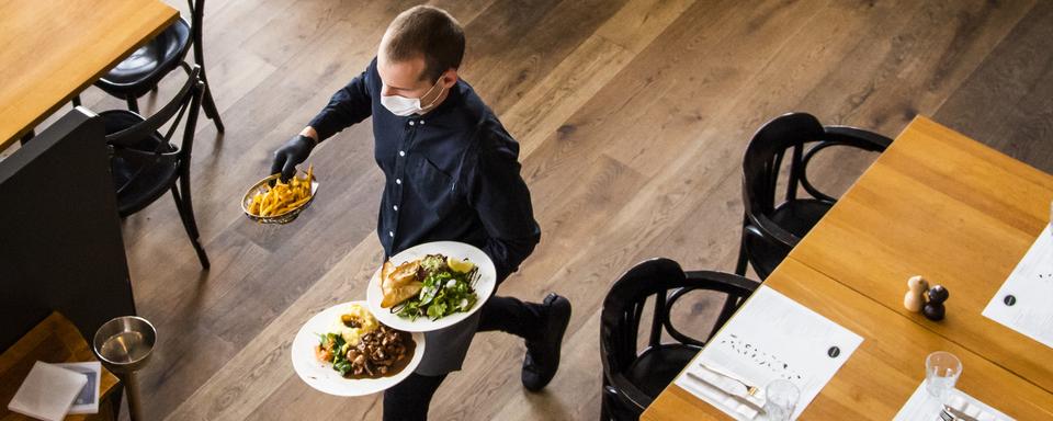 Un serveur au travail dans une brasserie lausannoise au mois de mai 2020. [Keystone - Jean-Christophe Bott]