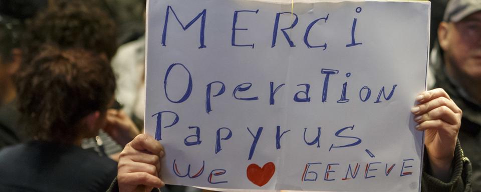 Une femme sans-papiers montre un panneau "Merci Operation Papyrus". [Keystone - Salvatore Di Nolfi]