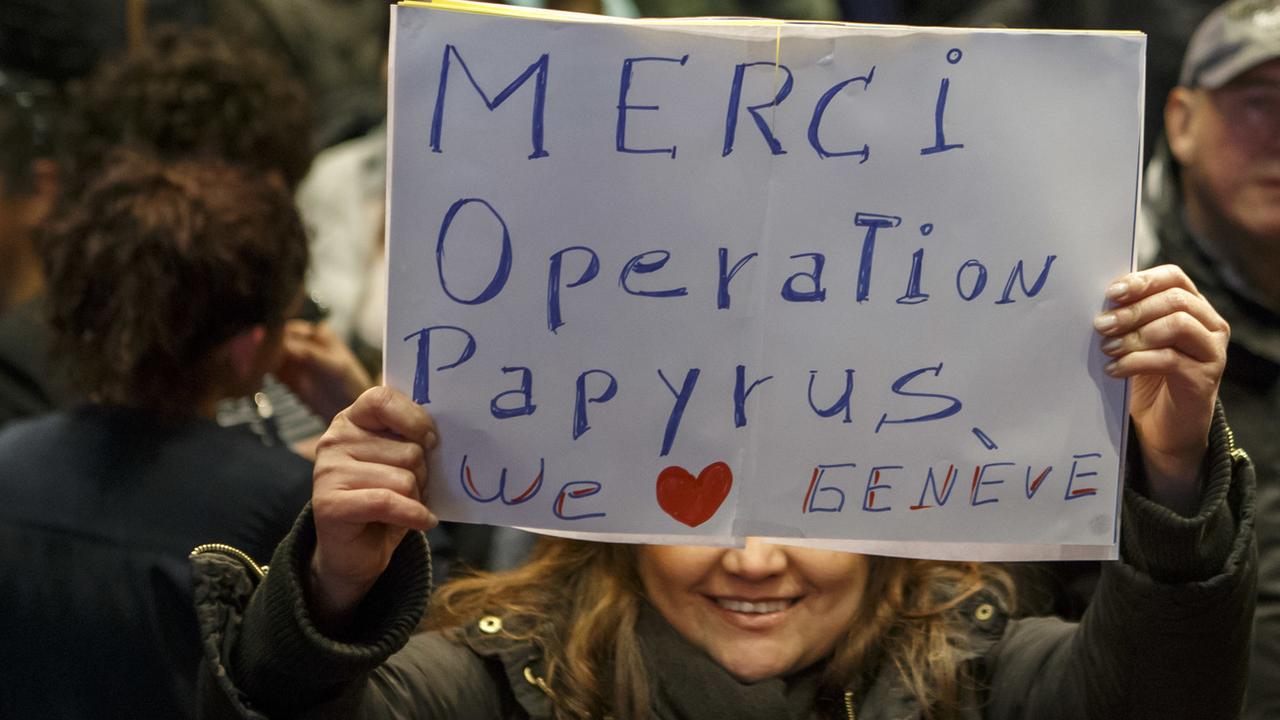 Une femme sans-papiers montre un panneau "Merci Operation Papyrus". [Keystone - Salvatore Di Nolfi]