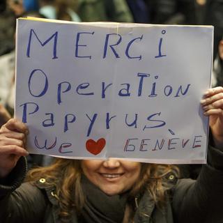 Une femme sans-papiers montre un panneau "Merci Operation Papyrus". [Keystone - Salvatore Di Nolfi]