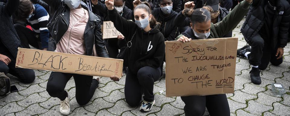 La foule à Lausanne a observé le silence pendant 8 minutes 46 secondes, un genou à terre et un poing levé en hommage à George Floyd. [Keystone - Jean-Christophe Bott]