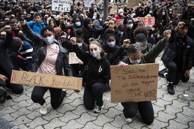 La foule à Lausanne a observé le silence pendant 8 minutes 46 secondes, un genou à terre et un poing levé en hommage à George Floyd. [Keystone - Jean-Christophe Bott]