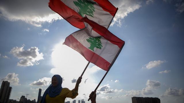 Des femmes libanaises agitent le drapeau libanais durant une commémoration pour les victimes de l'explosion au port de Beyrouth. [AFP - Patrick Baz]