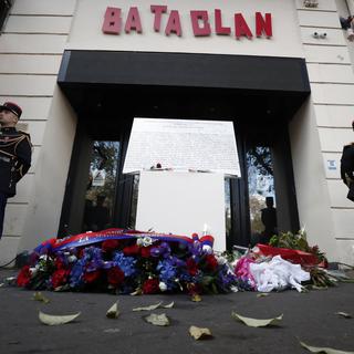 Une plaque commémorative et des fleurs déposées devant le Bataclan à Paris. [Keystone/AP - Benoît Tessier]