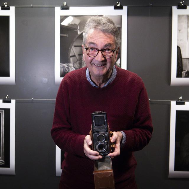 Le photographe Jean-Claude Péclet pose avec son appareil photo Rolleiflex dans le cadre de son exposition "Bobines neuves" au Musée suisse de l'appareil photographique. [Keystone - Laurent Gillieron]