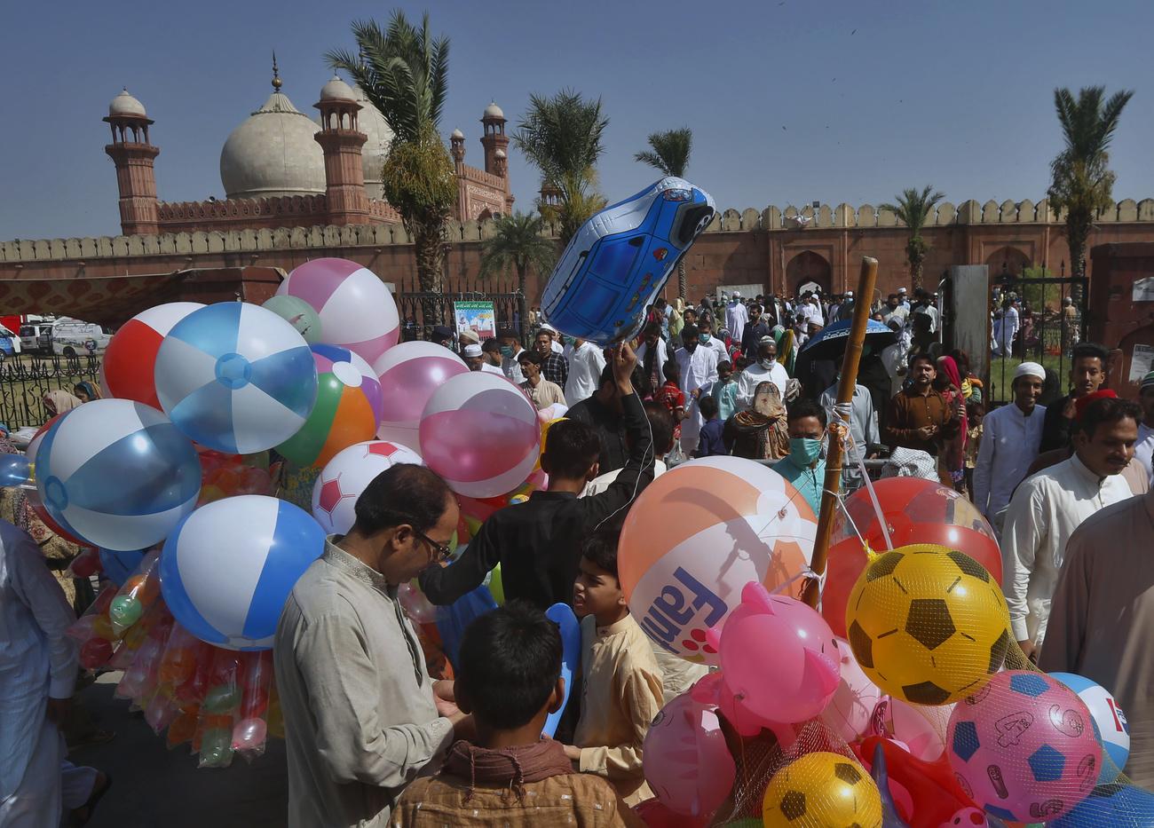 Au Pakistan, les musulmans achètent des ballons aux enfants devant une mosquée à Lahore, à l'occasion de l'Aïd. [Keystone - K.M. Chaudary]