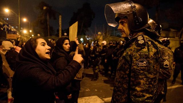 Une femme parle à un policier après un hommage aux victimes du crash du vol d'Ukrainian Airlines près de l'université de Téhéran. [AFP/ISNA - Mona Hoobehfekr]