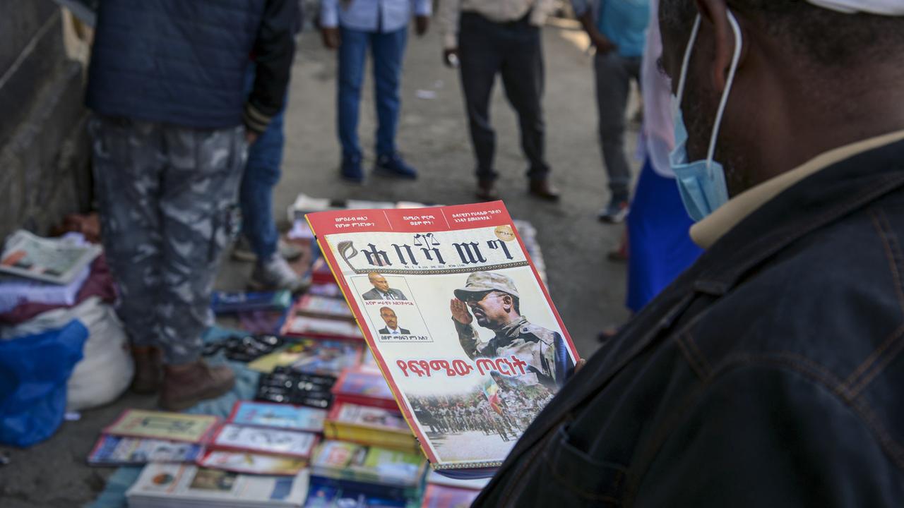 Des Ethiopiens lisent des magazines consacrés à la confrontation militaire. [Keystone - Samuel Habtab/AP]