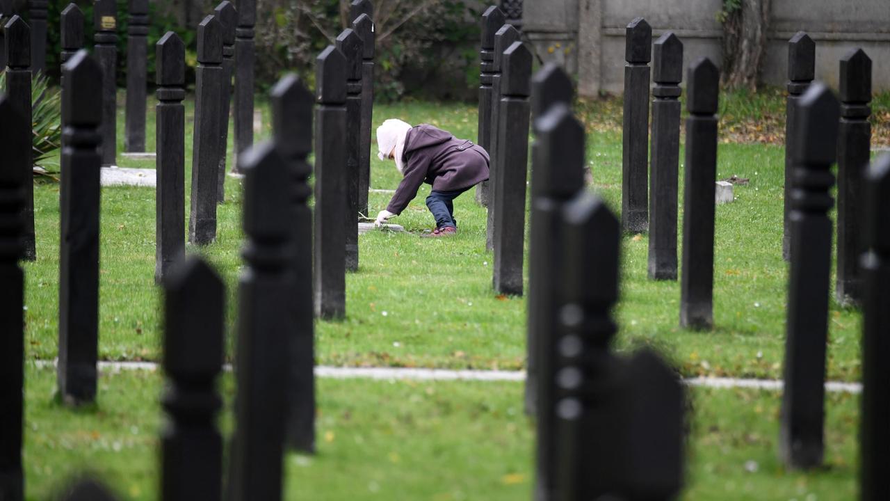 Une petite fille dépose des fleurs sur les tombes des victimes de la répression sanglante du 4 novembre 1956 en Hongrie. [AFP - ATTILA KISBENEDEK]