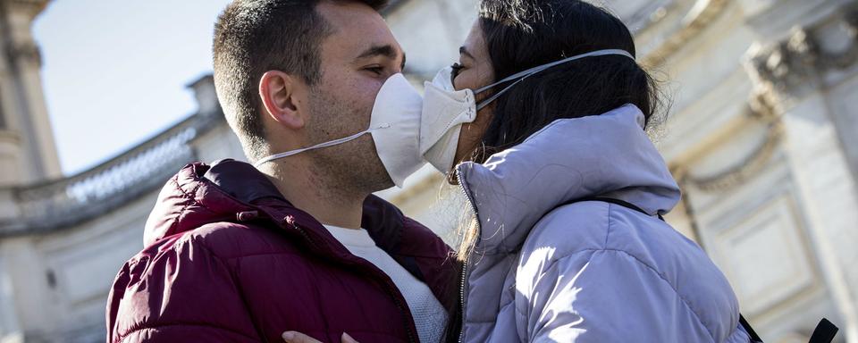 Deux jeunes qui s'embrassent avec un masque. [Keystone - EPA/Massimo Percossi]