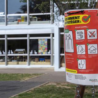 Une affiche des règles de prévention du Covid-19 devant une école primaire de Genève. [Keystone - Martial Trezzini]