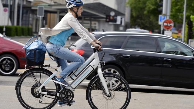 Une cycliste au volant d'un vélo électrique. [Keystone - Walter Bieri]