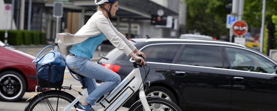 Une cycliste au volant d'un vélo électrique. [Keystone - Walter Bieri]