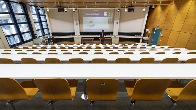 Un professeur donne un cours par vidéoconférence à ses étudiants depuis un auditoire vide de l'EPFL, le 13 mars 2020. [Keystone - Jean-Christophe Bott]