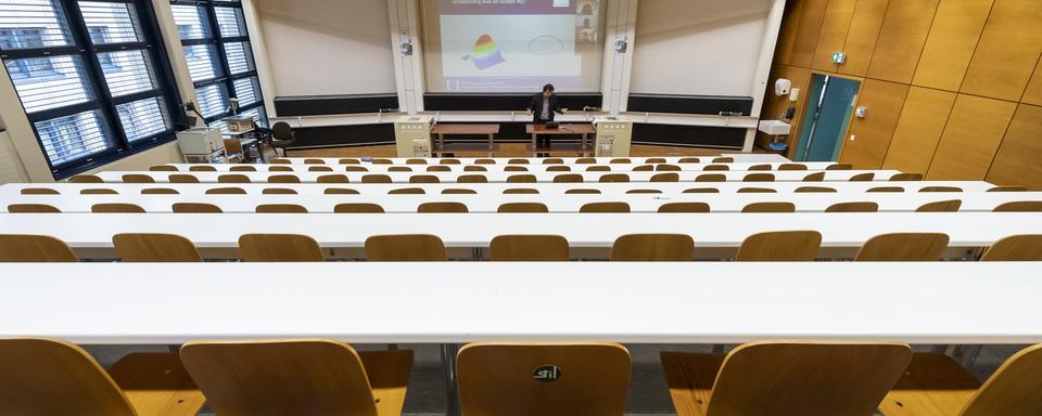 Un professeur donne un cours par vidéoconférence à ses étudiants depuis un auditoire vide de l'EPFL, le 13 mars 2020. [Keystone - Jean-Christophe Bott]