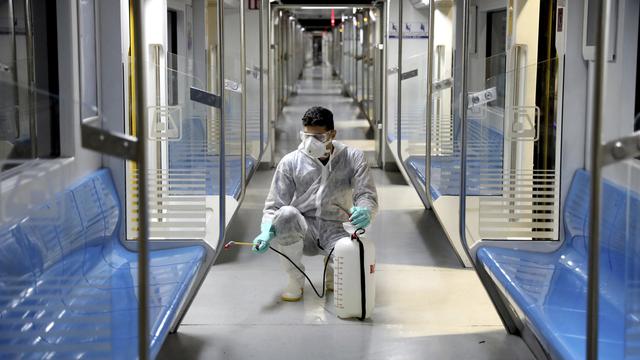 Un homme désinfectant un métro à Téhéran. [AP Photo/Keystone - Ebrahim Noroozi]