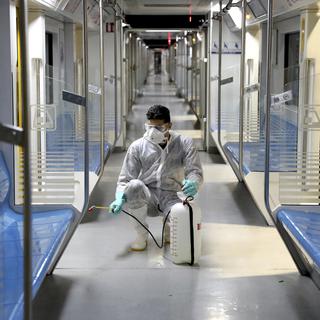 Un homme désinfectant un métro à Téhéran. [AP Photo/Keystone - Ebrahim Noroozi]