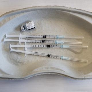Un "haricot" contenant des seringues et une dose de vaccin contre le Covid-19. [Keystone - Jean-Christophe Bott]
