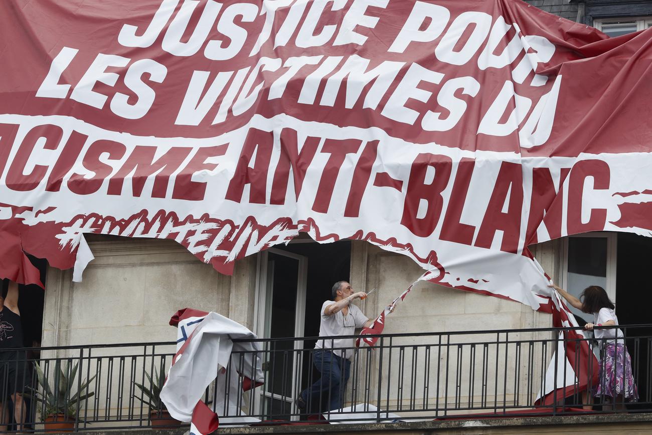 Des militants identitaires ont déployé une banderole: "Justice pour les victimes du racisme anti blanc". [Keystone - AP Photo/Thibault Camus]