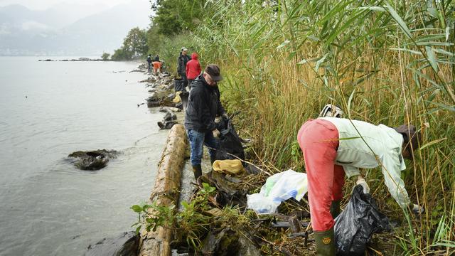 Des personnes volontaires ramassent des déchets sur les rives du Léman à Noville (VD). [Keystone - Laurent Gillieron]