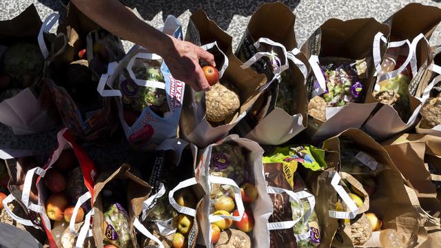 Des bénévoles de la structure "Le Point d'Appui" remplissent des sacs de nourriture avant de les donner aux personnes dans la précarité à l'occasion d'une distribution alimentaire lors de la crise du Coronavirus (Covid-19) le mercredi 20 mai 2020 à Lausanne. [Keystone - Jean-Christophe Bott]