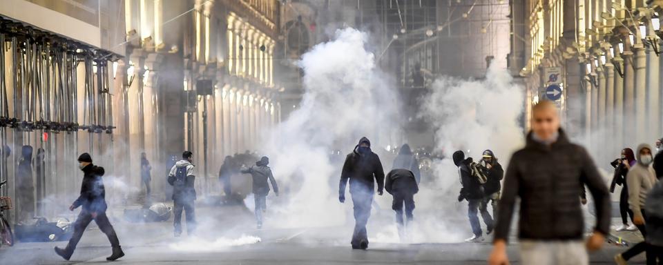 Affrontements entre policiers et manifestants anti-couvre-feu dans les rues de Turin. [Keystone/La Presse via AP - Claudio Furlan]