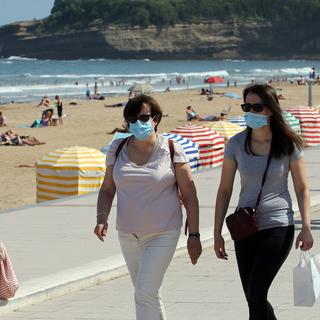 Des gens masqués à côté d'une plage à Biarritz. [AP/Keystone - Bob Edme]