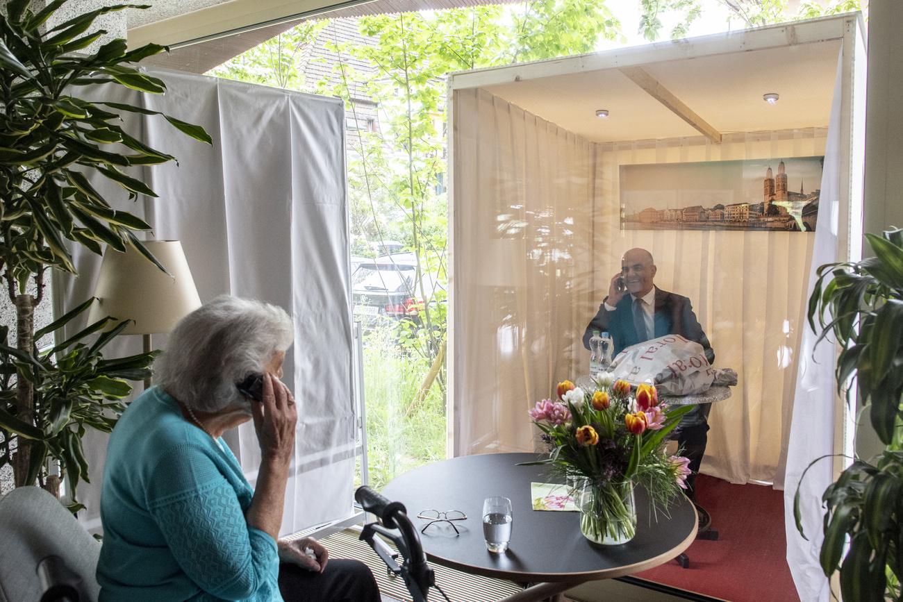 30 avril: le ministre de la Santé Alain Berset converse avec la résidente d'un EMS zurichois à travers une vitre. [Keystone - Ennio Leanza]
