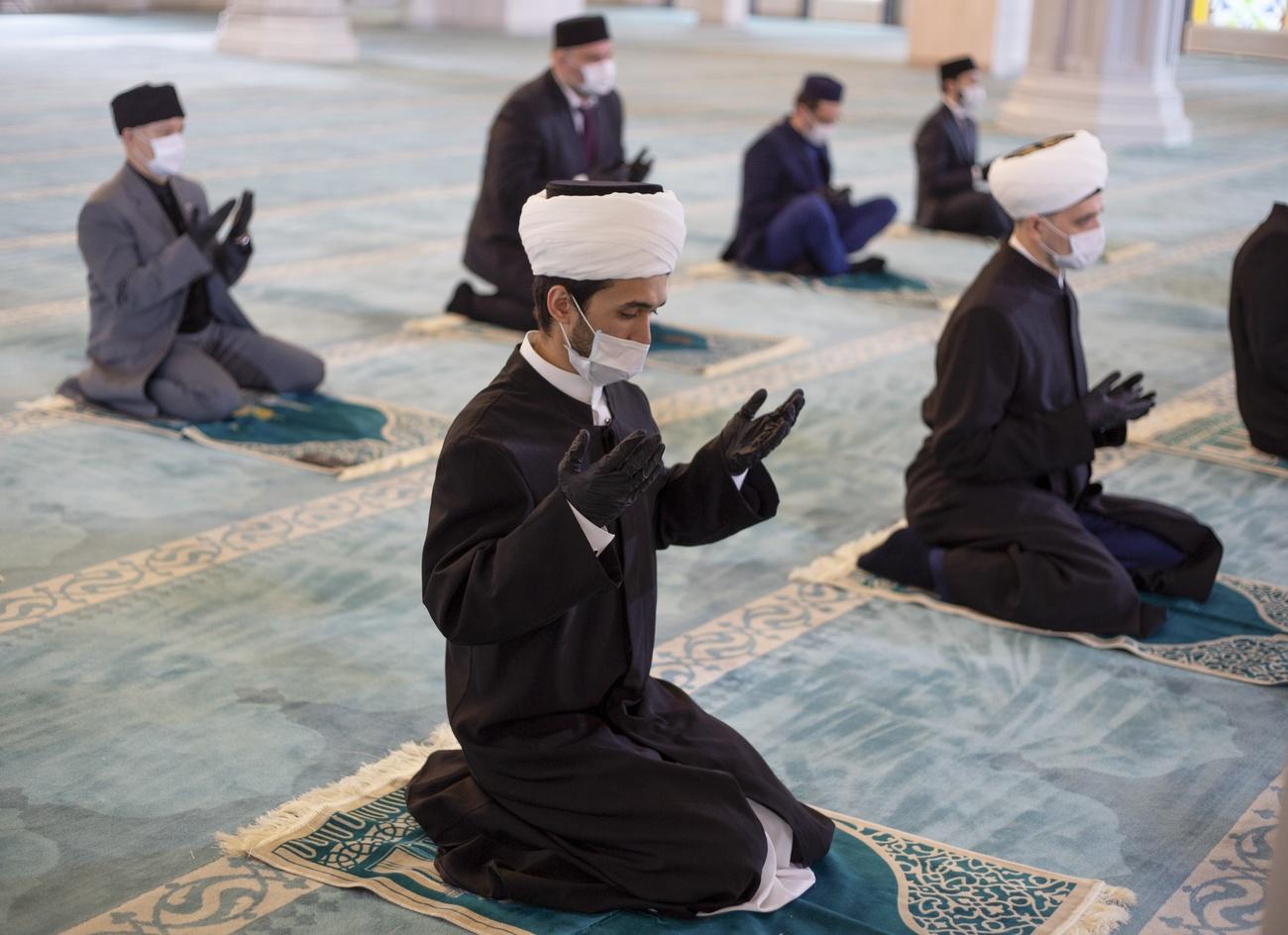 En Russie, des représentants religieux portent des masques et des gants pour faire la prière de l'Aïd dans la grande mosquée de Moscou. [Keystone - Conseil des Muftis russes]