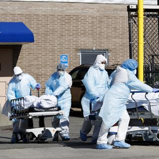 Des travailleurs de la santé transportent deux personnes décédées du SARS-CoV-2 à l'extérieur du Wyckoff Heights Medical Center, à Brooklyn, à New York, le 6 avril 2020. [Keystone/epa - Justin Lane]