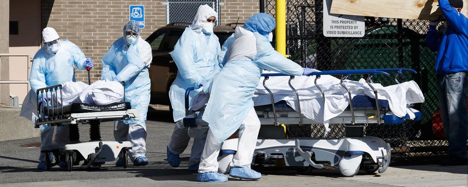 Des travailleurs de la santé transportent deux personnes décédées du SARS-CoV-2 à l'extérieur du Wyckoff Heights Medical Center, à Brooklyn, à New York, le 6 avril 2020. [Keystone/epa - Justin Lane]