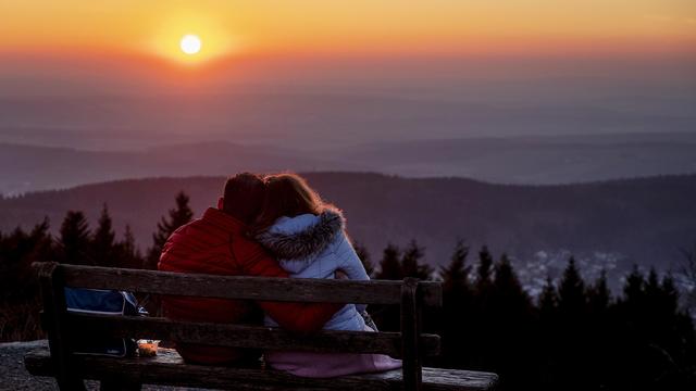 Un couple sur un banc regarde le coucher du soleil près de Francfort. [AP PHoto/Keystone - Michael Probst]