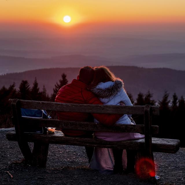 Un couple sur un banc regarde le coucher du soleil près de Francfort. [AP PHoto/Keystone - Michael Probst]