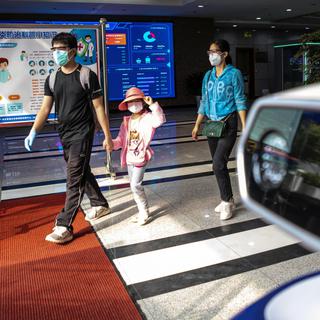 Un robot contrôle la température des visiteurs pour détecter les cas de coronavirus en Chine. [EPA/Keystone - Alex Plavevski]