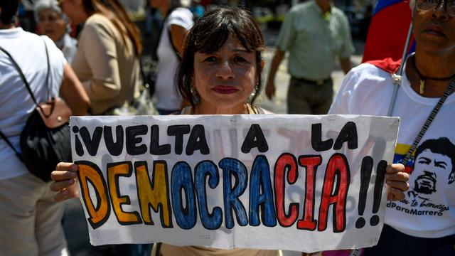 Une manifestante tenant une pancarte "Retour à la démocratie" à Caracas en Colombie. [AFP - Federico PARRA]