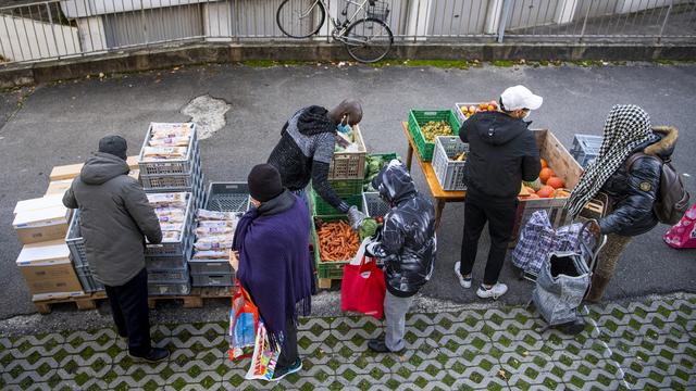 Des bénévoles de l'association Solid-ère distribuent des sacs alimentaires à Lausanne. [Keystone - Jean-Christophe Bott]