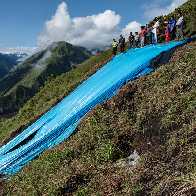 "Humans and climate change stories": Pérou: La montagne qui surplombe la ville de Santa Teresa menace de s'effondrer. Pour freiner le glissement de terrain, une bâche a été tendue et une messe de bénédiction est célébrée. [DR - Marion Esnault]