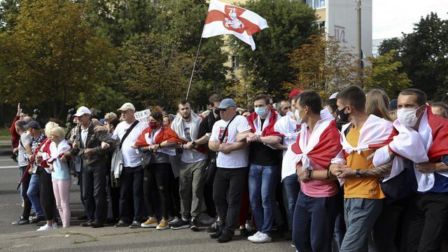 Des manifestants défilent dans les rues de Minsk, ralliés derrière l'ancien drapeau biélorusse. [Keystone/TUT.by via AP]