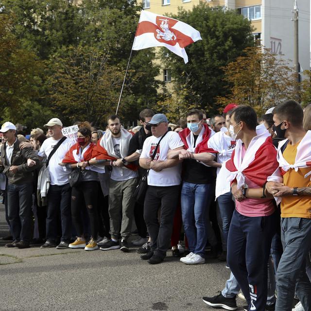 Des manifestants défilent dans les rues de Minsk, ralliés derrière l'ancien drapeau biélorusse. [Keystone/TUT.by via AP]