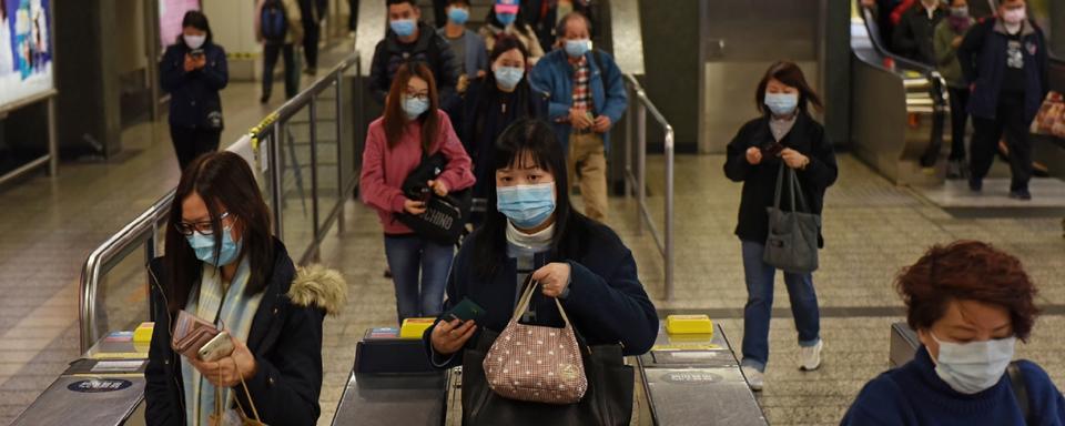 Pendulaires portant des masques dans une station de métro à Hong Kong suite à l'émergence du coronavirus. [EPA / Keystone - MIGUEL CANDELA]