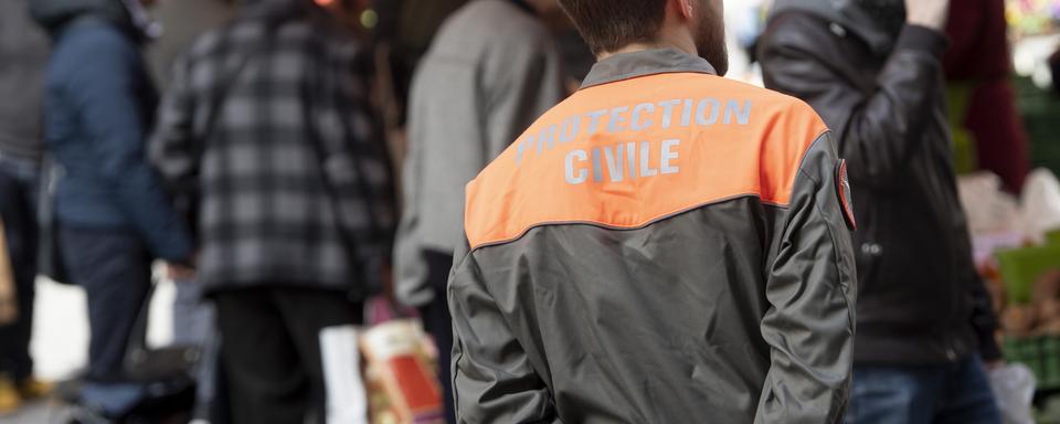 Un membre de la Protection civile patrouille au marché de Lausanne pour distribuer des flyers. [Keystone - Laurent Gilliéron]