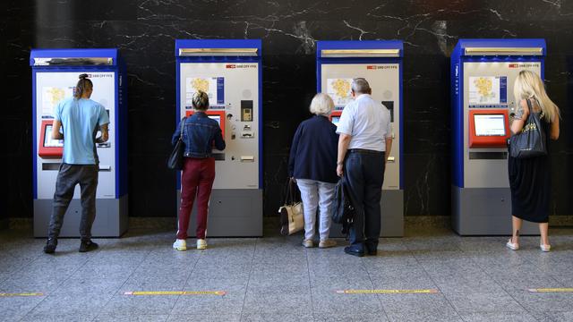 Des personnes achètent des billets à des distributeurs de billets à la gare CFF de Bienne. [KEYSTONE/Anthony Anex]