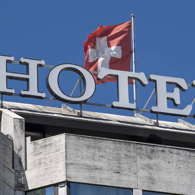 Le mot hôtel est photographie à coté du drapeau suisse, ce mercredi 5 août 2020 à Genève. [KEYSTONE - Martial Trezzini]