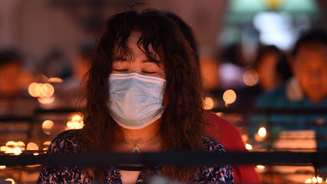 Une fidèle portant un masque comme mesure préventive contre le coronavirus, prie dans une église. [AFP - TED ALJIBE]