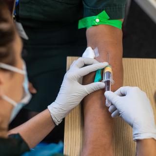 Une soignante effectue un prélèvement sanguin en vue d'un test de dépistage du Covid-19. [EPA/Keystone - Simon Dawson]