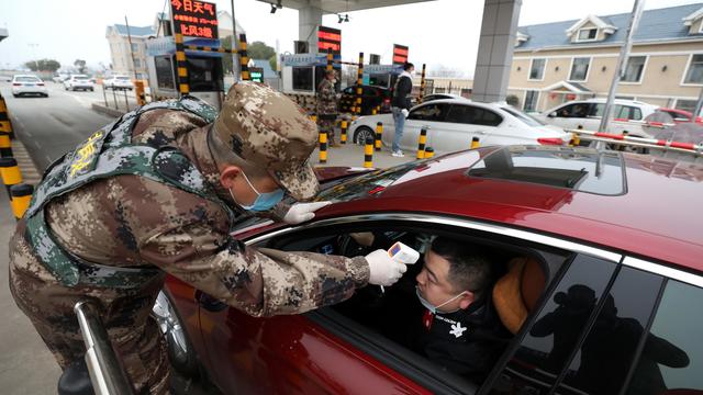 Un automobiliste se soumet à une prise de température à un péage autoroutier à Wuhan, en Chine. [Keystone - EPA/YUAN ZHENG]