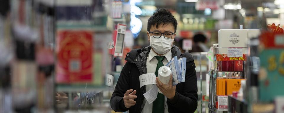 Un client d'une pharmacie à Hong Kong, en pleine épidémie de coronavirus. [Keystone - Jérôme Favre / EPA]